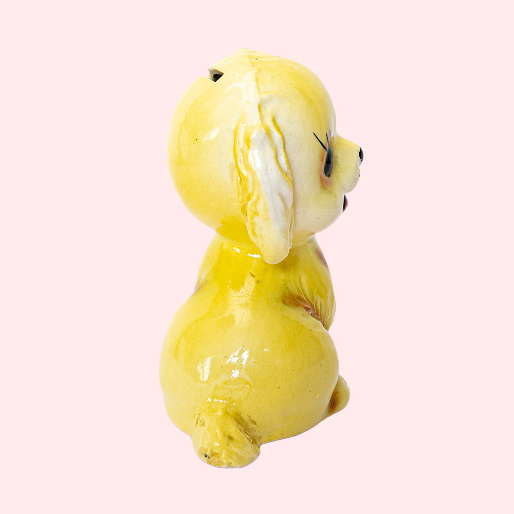 Second-hand, vintage Japan-style ceramic piggy bank from the 50's, representing a golden retriever with big eyes. Seen from the side.