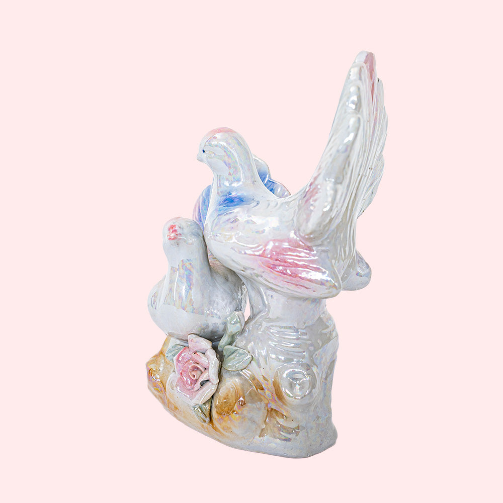 Second-hand, decorative ceramic figurine representing two doves with colorful wings and tails. It has an iridescent glaze. Seen from the side.