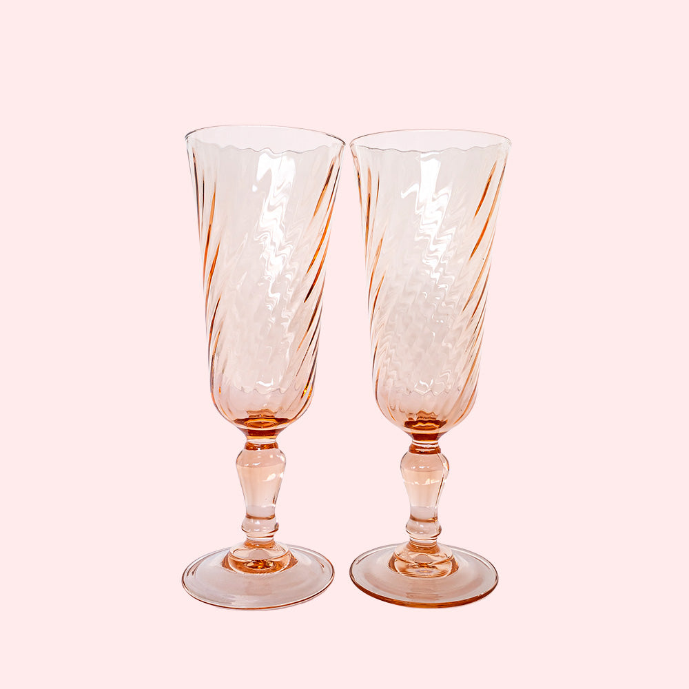 Two vintage pink champagne flutes with a swirl design.