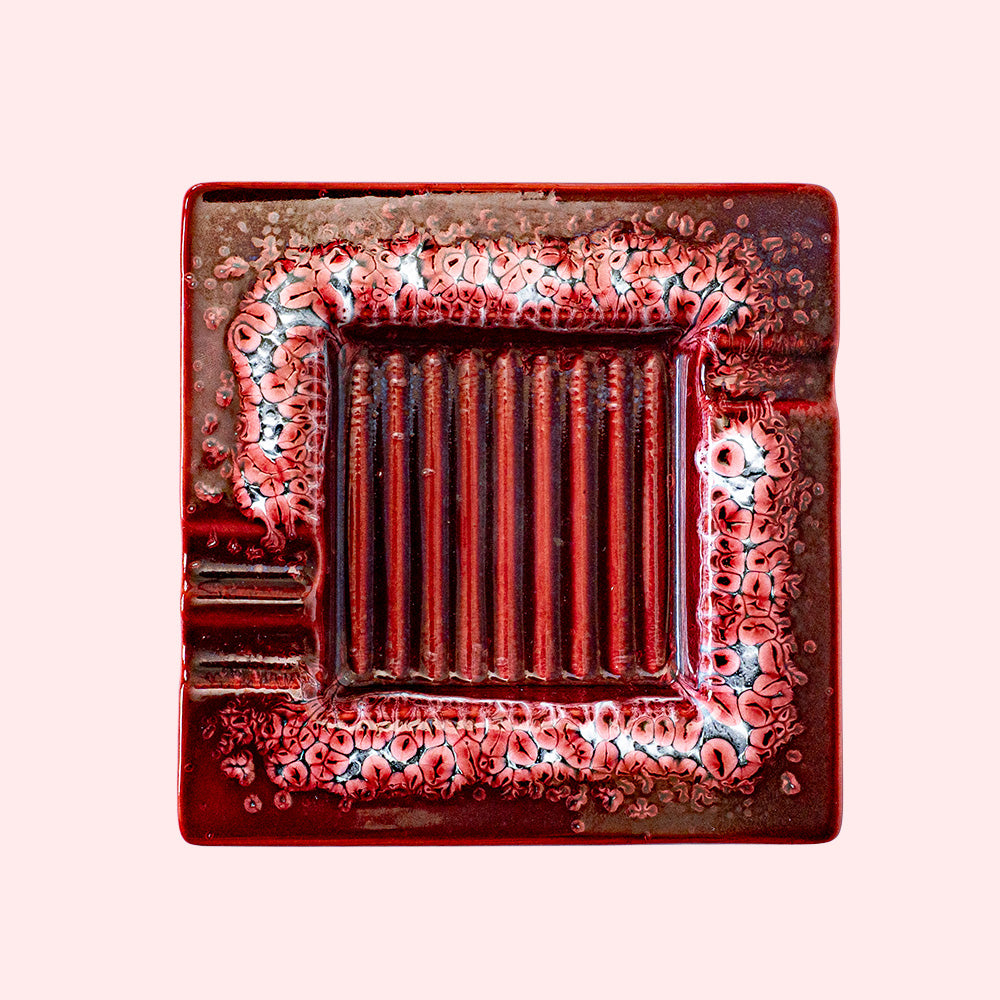 Decorative red ceramic ashtray with a ridged inside surface. Seen from above.