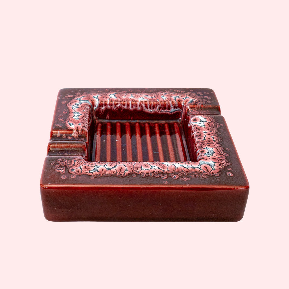 Decorative red ceramic ashtray with a ridged inside surface.