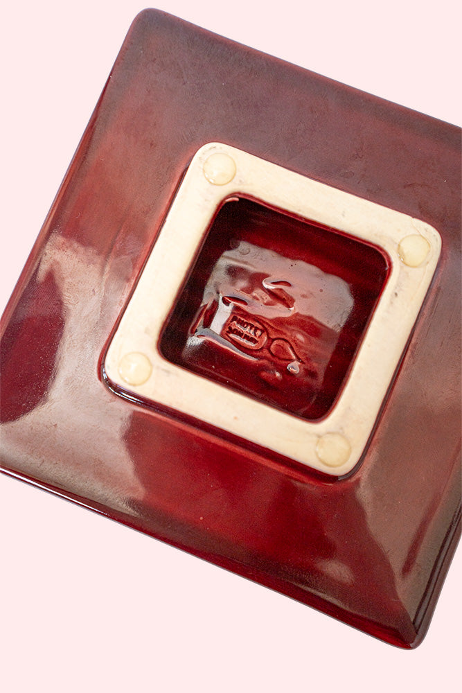 Decorative red ceramic ashtray with a ridged inside surface. Seen from the underside with Protet's signature.