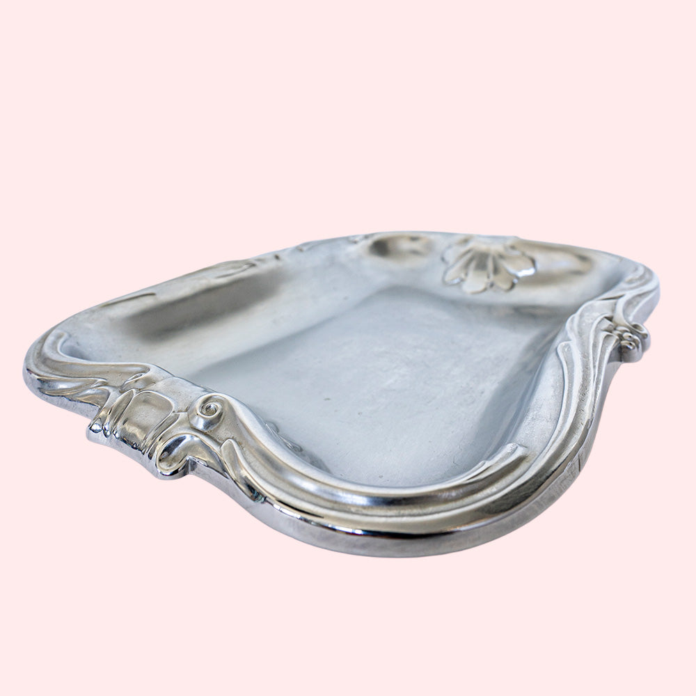 A vintage stainless steel tray with decorative edges.