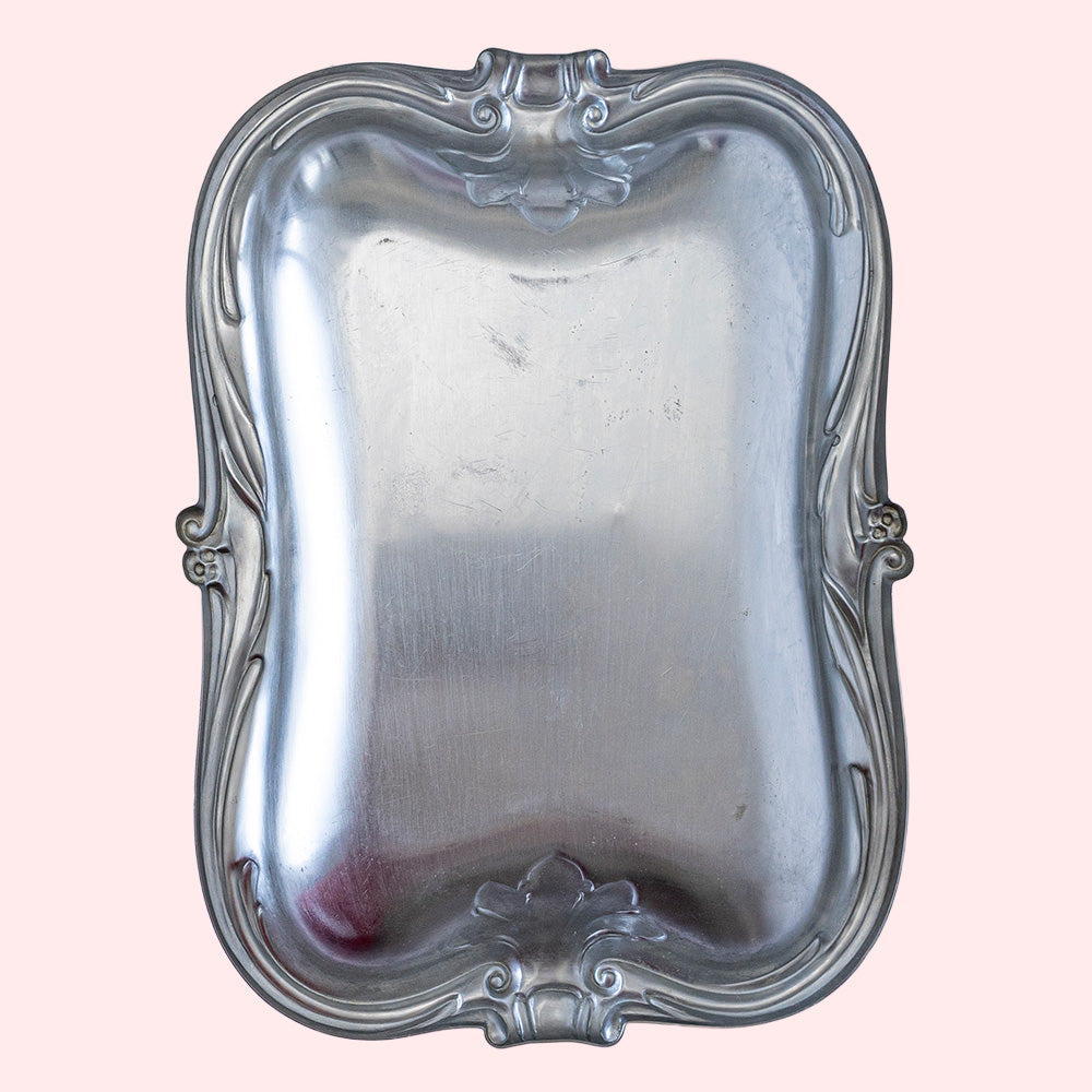 A vintage stainless steel tray with decorative edges. Seen from the bottom side.