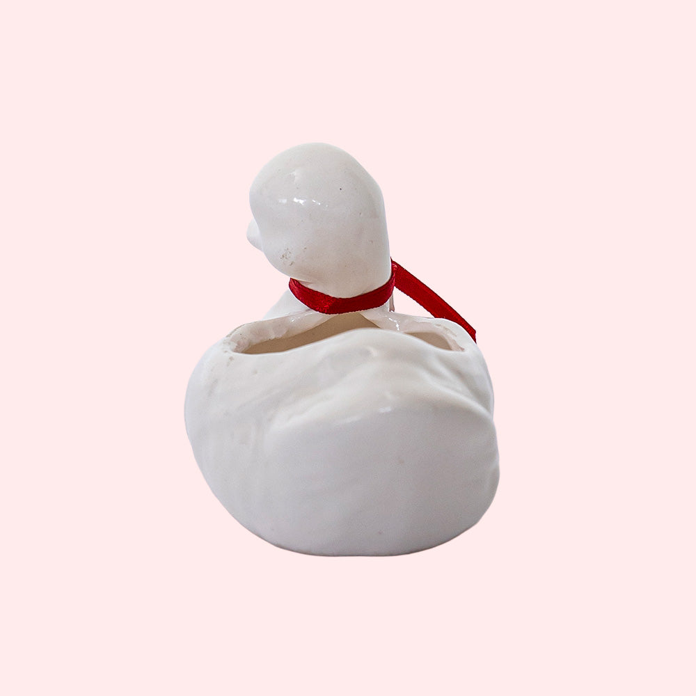 A vintage hollow porcelain duck with a red ribbon around its neck