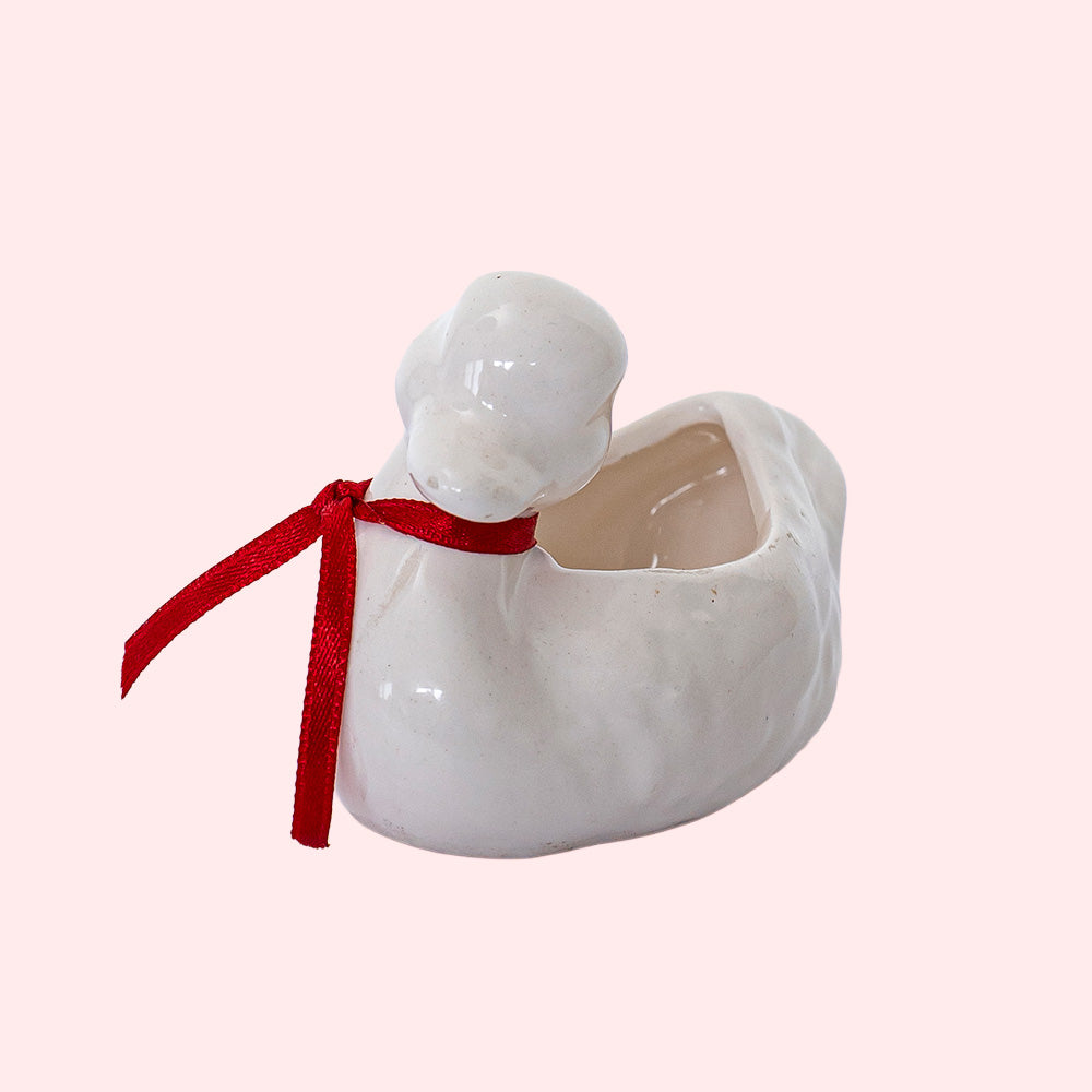 A vintage hollow porcelain duck with a red ribbon around its neck
