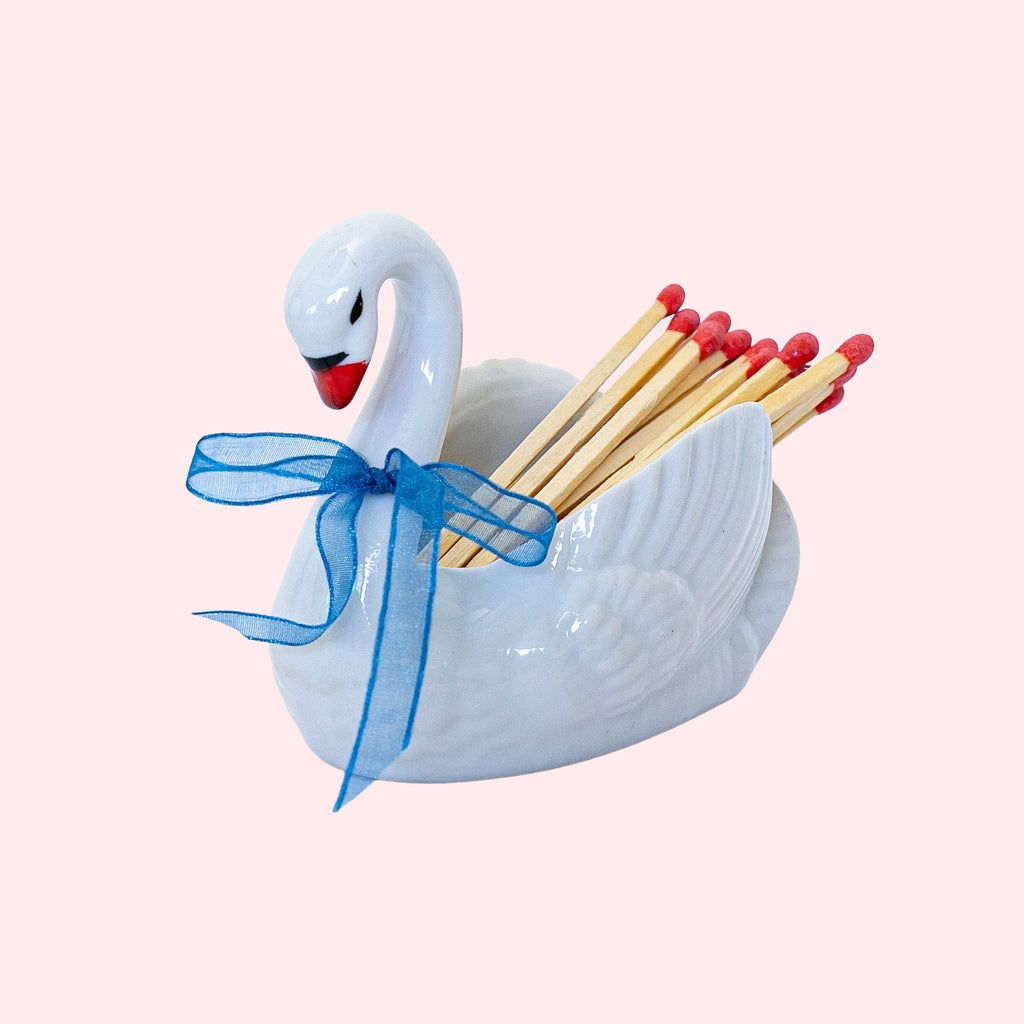 Second-hand ceramic, hollow swan figurine filled with 20 matches. It's wearing a blue organza ribbon.  