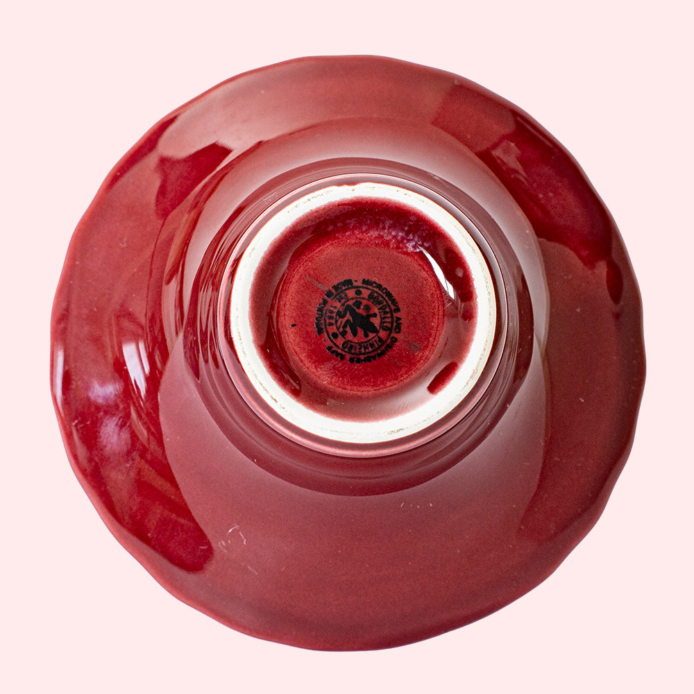 A burgundy colored tealight holder with intricate heart patterns. Seen from the bottom side.