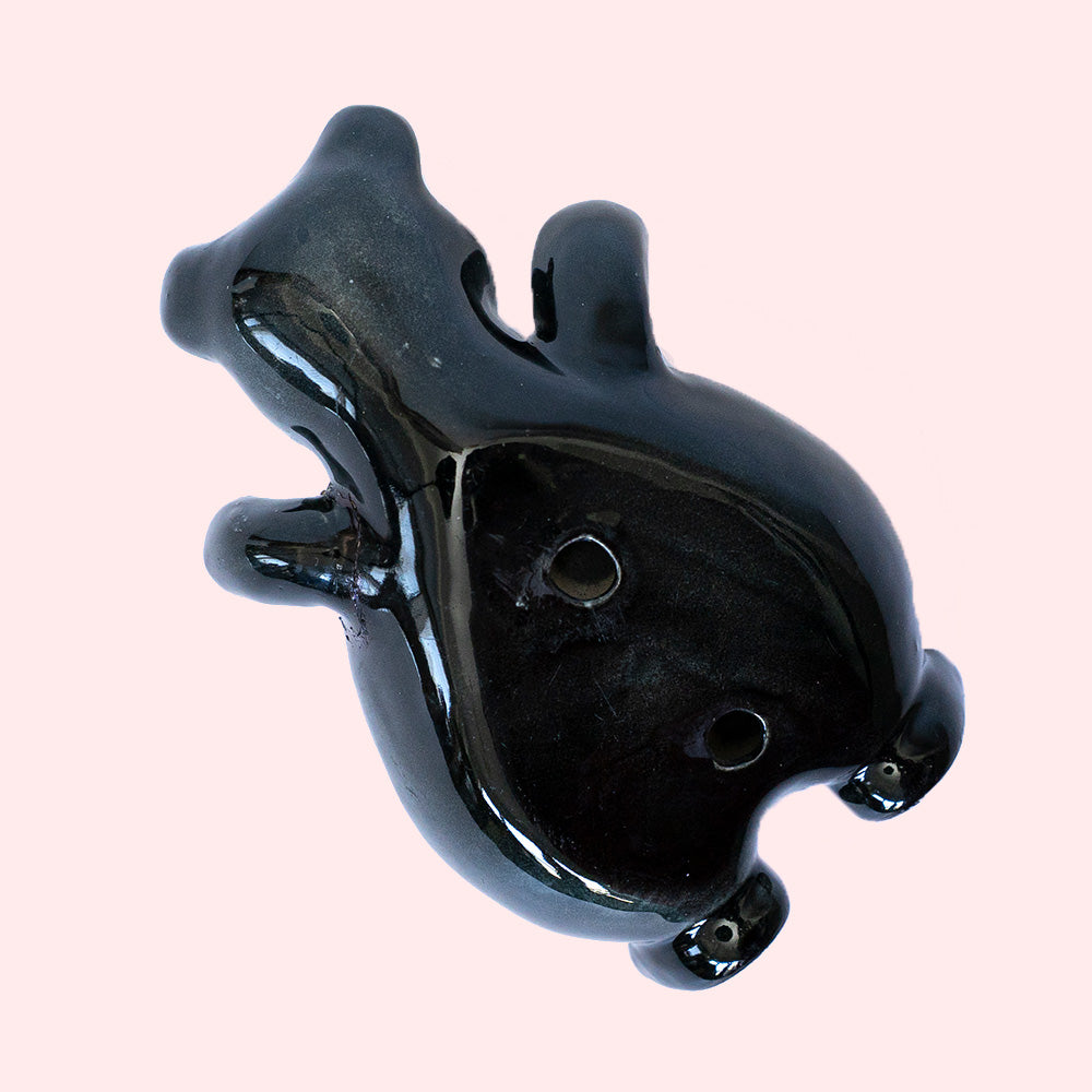 Second hand vintage trinket dish. It represents a black bear with a grey-white face, with his arms open. Seen from the underside.